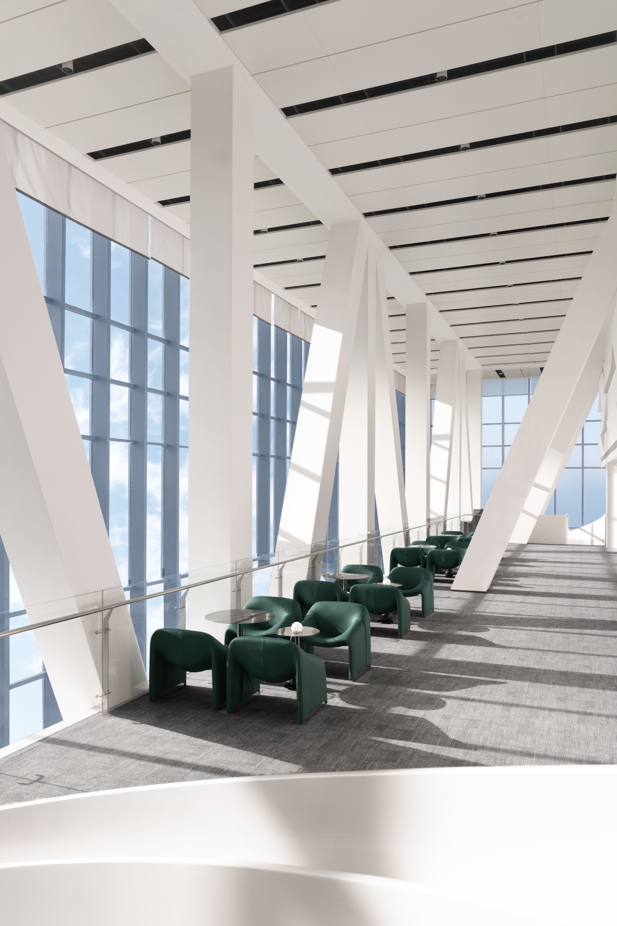 Sunlit contemporary interior with white structural columns and green lounge chairs