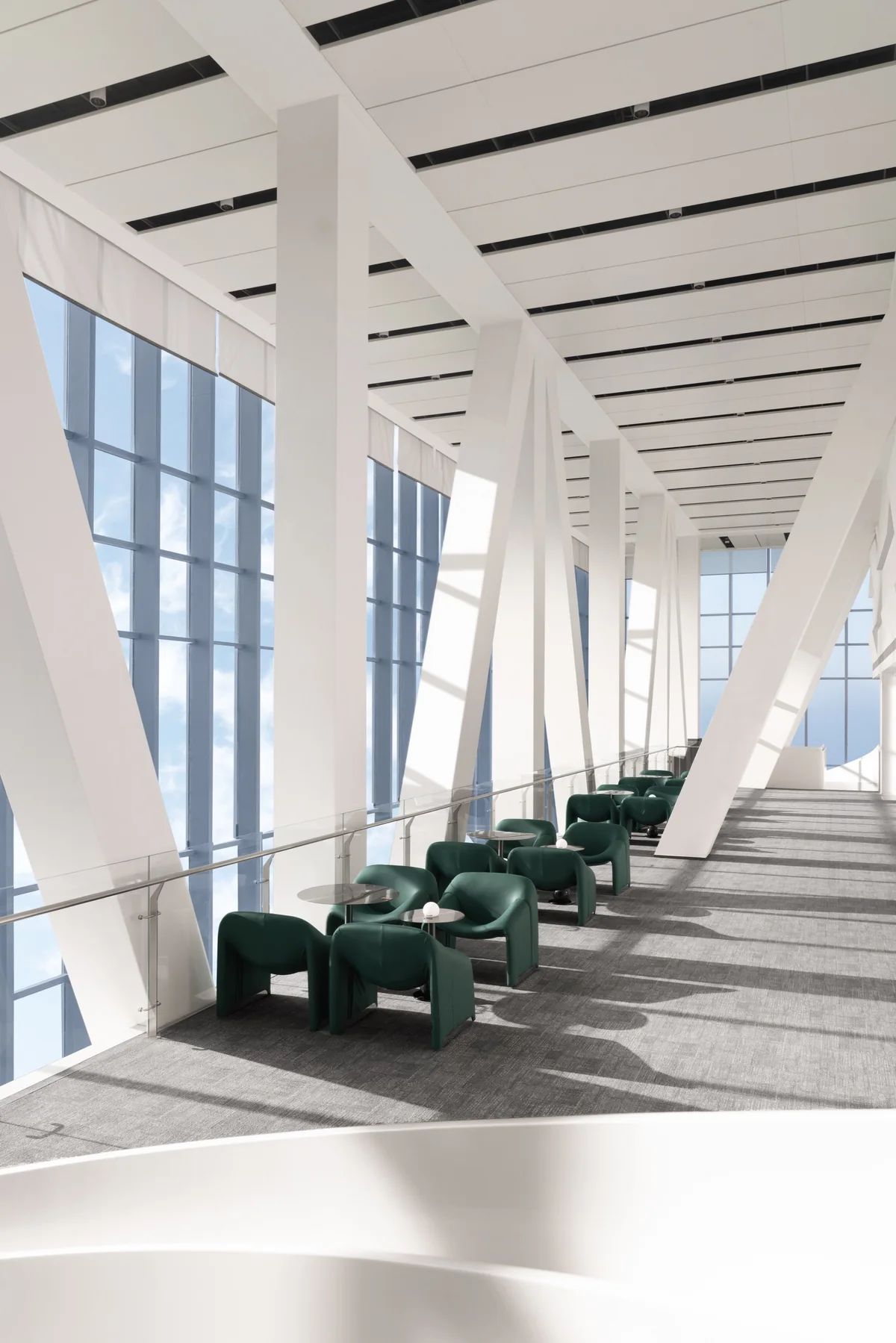 Sunlit contemporary interior with white structural columns and green lounge chairs